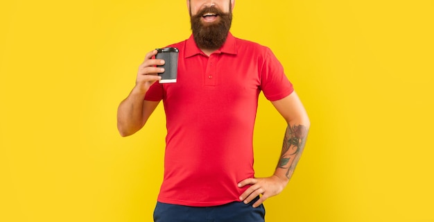 Happy bearded man crop view in casual red tshirt holding coffee cup with arm akimbo takeaway