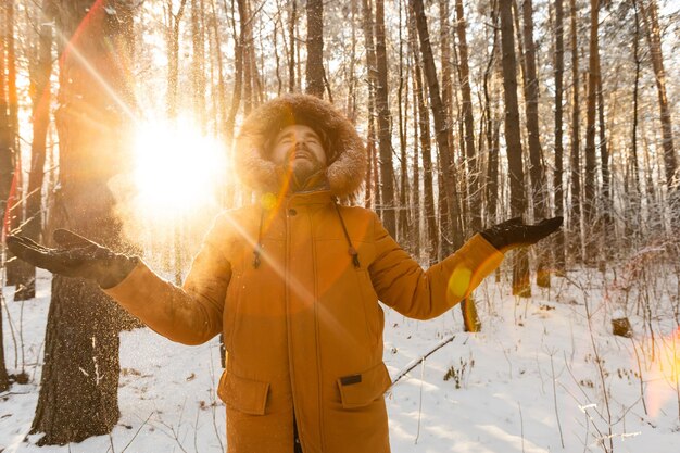 Foto uomo barbuto felice con cappello vomita neve in inverno natura nevosa stagione fredda e vacanze stile di vita