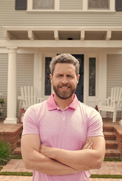 Счастливый бородатый мужчина возле нового дома после аренды или покупки нового дома
