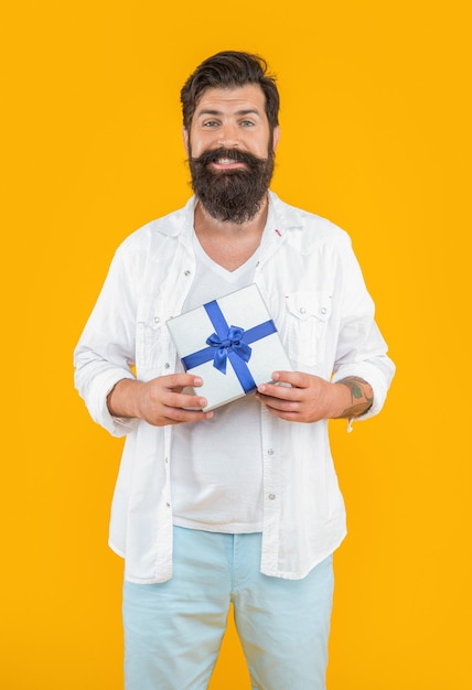 Happy bearded man offer sale gift isolated on yellow man offer sale gift in studio