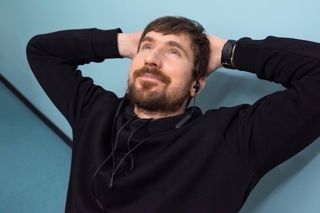 Happy bearded man relaxing in the office workplace listening to music on headphones