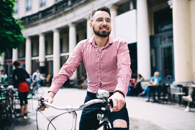 Happy bearded man riding bicycle along urban street