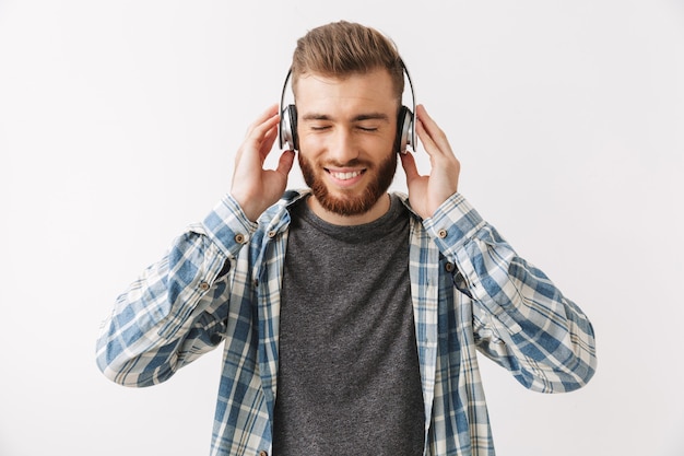 Happy bearded man in shirt and headphones listening music