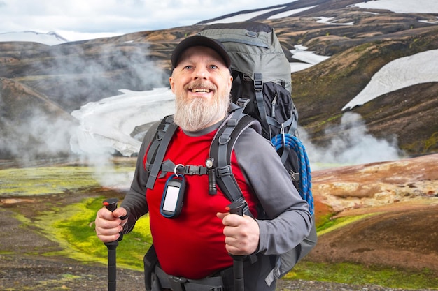 山の背景にハイキング機器を備えた幸せなひげの男の旅行者