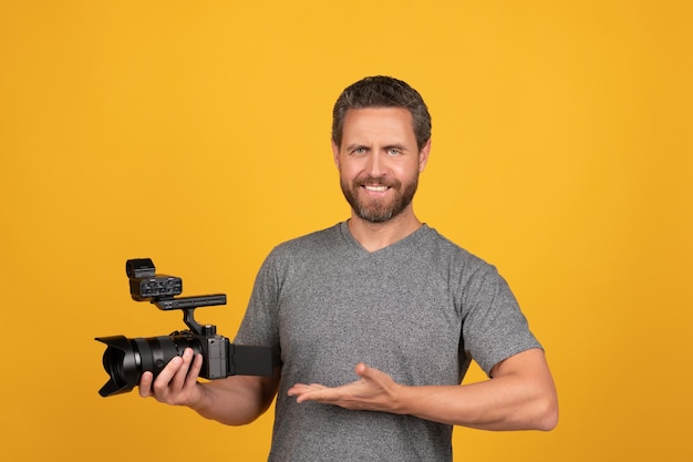 Happy bearded man videographer presenting professional camcorder product proposal