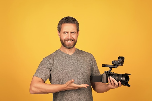 Happy bearded man videographer presenting professional camcorder product proposal