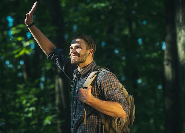 Счастливый бородатый мужчина с рюкзаком гуляет по лесу, экотуризм, активные летние каникулы