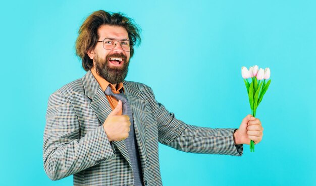 Happy bearded man with flowers showing thumb up businessman with bouquet of tulips for birthday