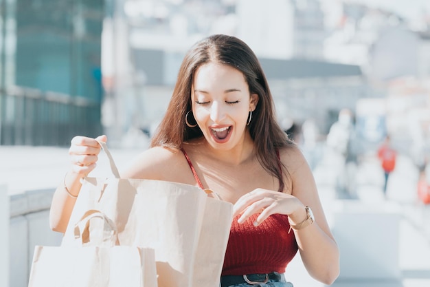 Photo happy beautiful african modern woman looking inside shopping bag surprised about what is inside