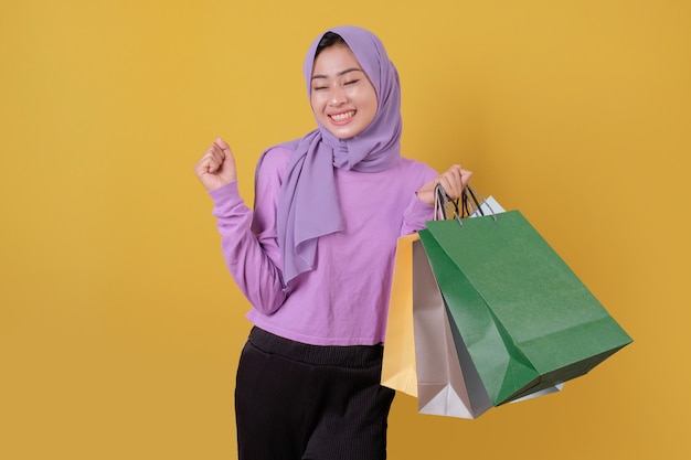 ショッピングバッグを持っている幸せな美しいアジアの買い物中毒の女性