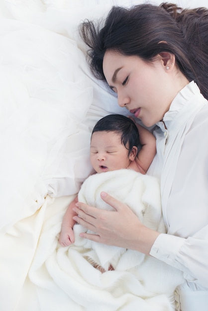 Happy beautiful asian woman looking at her sleeping baby child