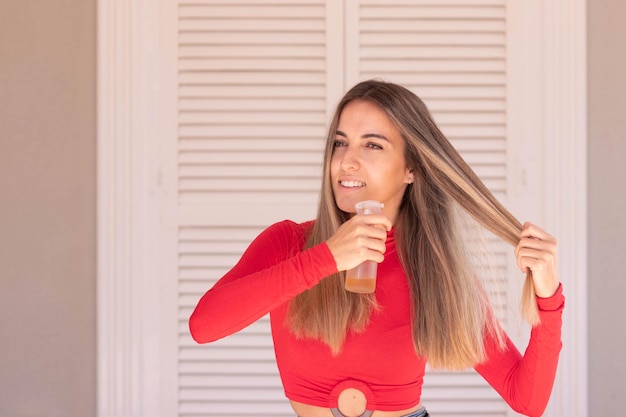 Happy beautiful and attractive woman looking to the side while appying beauty treatment into her healthy hair