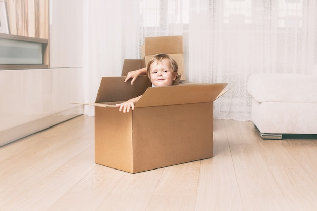 Happy and beautiful baby smiling at home in the living room sitting in a cardboard box