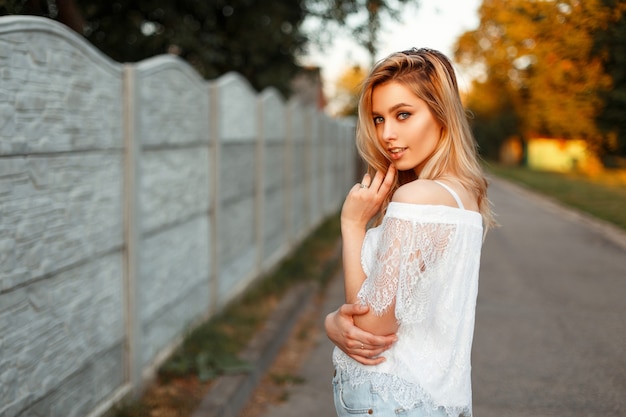 Happy beautiful blond woman in a white lace top outdoors