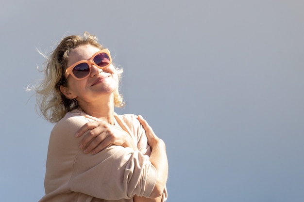 Felice bella donna caucasica bionda con gli occhiali ride mentre guarda la telecamera. donna in una giornata di sole.