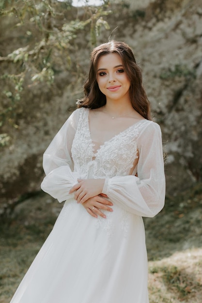 Felice bella sposa fuori su un prato estivo al tramonto con vista perfetta