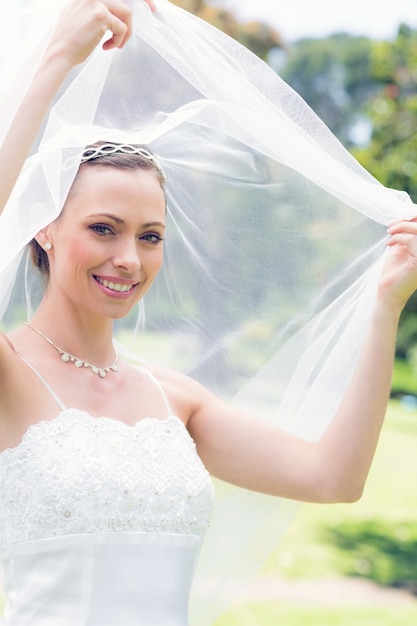 Photo happy beautiful bride unveiling self in garden