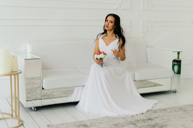 Happy beautiful bride with her veil smiling and excited in an interior, wedding morning