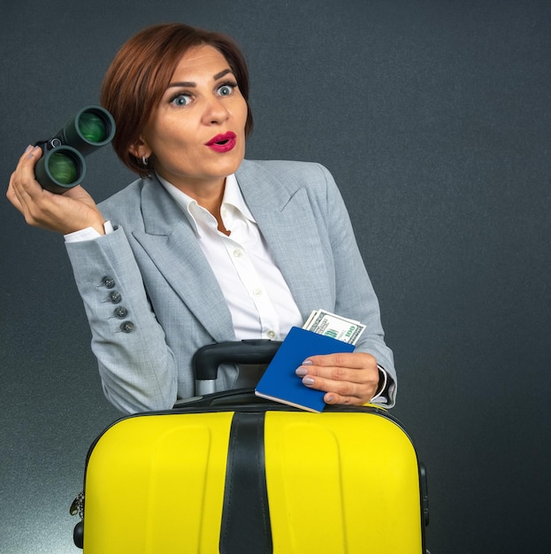 Happy beautiful business woman looks with binoculars in surprise towards her travel