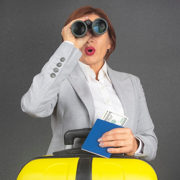 Happy beautiful business woman looks with binoculars in surprise towards her travel