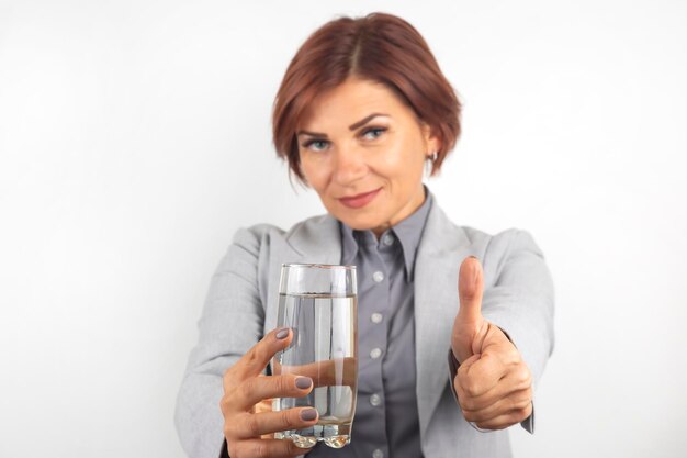 Happy beautiful business woman offers a glass of water. Thirst and health.