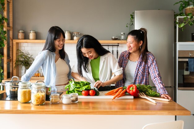 사진 행복한 아름다운 중국 여성 친구들이 집에서 유대감을 형성하고 함께 맛있는 식사를 요리합니다.