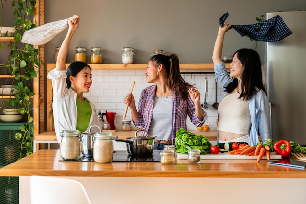 Happy beautiful chinese women friends bonding at home and cooking delicious meal together