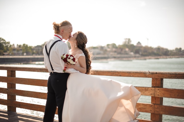 Foto felice bella coppia che si bacia sul molo di legno sul lago. concezione del matrimonio