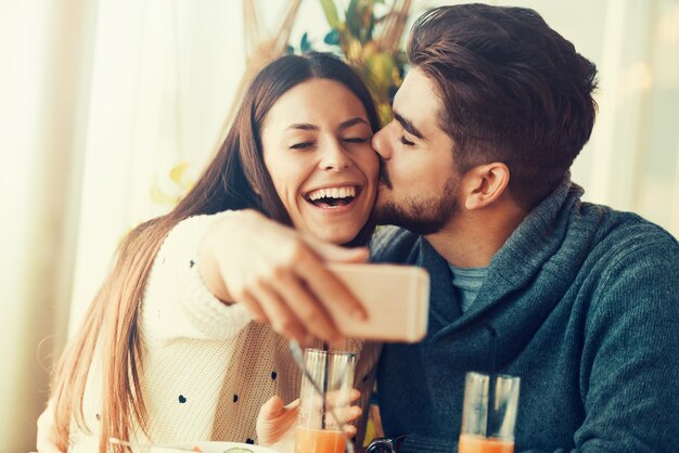 Happy beautiful couple using smart phone in cafe