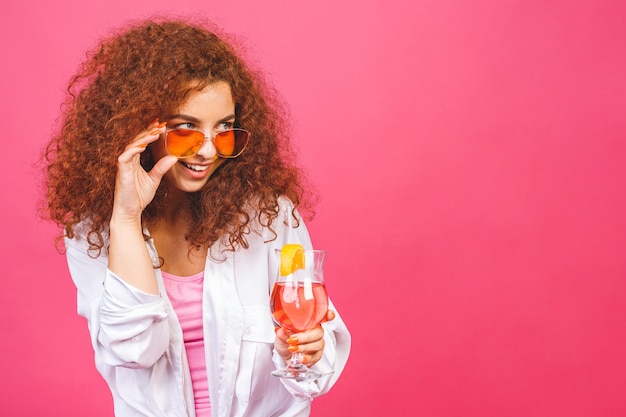 Счастливая красивая кудрявая женщина в летней повседневной одежде с бокалом коктейльного напитка
