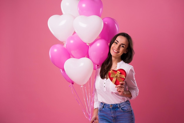 Happy beautiful cute lovely woman with colorful balloons and gift in hands is have a fun and celebration. Birthday, Holidays, St Valentines day and other