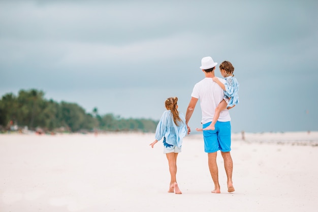 Happy beautiful family of dad and kids on white beach