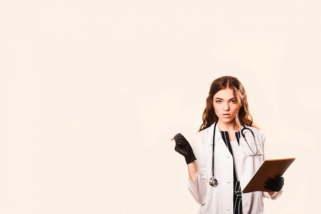 Happy beautiful female doctor in medical coat .Writes a medical history in notebook