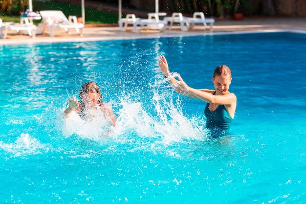 Happy beautiful girls having fun at the pool at the resort