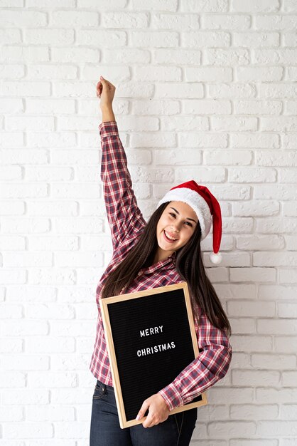 メリークリスマスという言葉で文字板と幸せな美しいラテン女性