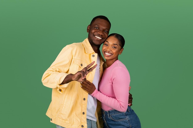 Photo happy beautiful millennial black couple posing on green background