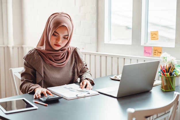 Happy beautiful muslim business woman  working about financial with business report and calculator in home office.