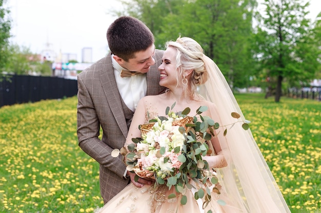 Happy and beautiful newlyweds walking in the park. Open-air wedding.