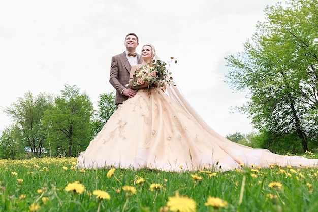 公園を歩いている幸せで美しい新婚夫婦。野外結婚式。