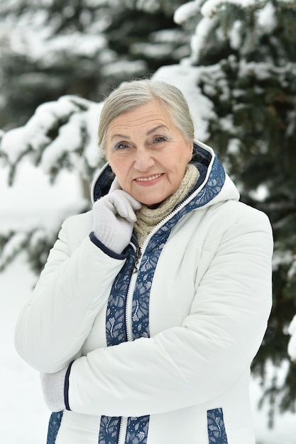 Happy beautiful senior woman posing in snowy winter park