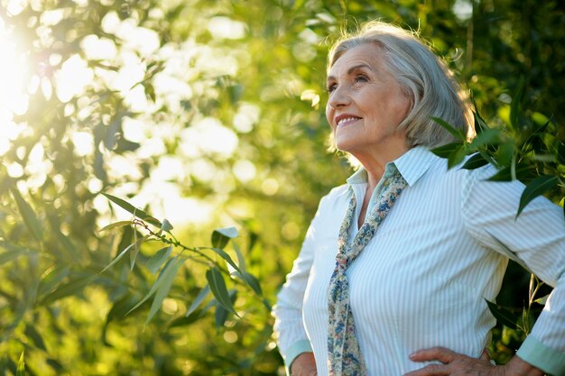 Happy beautiful senior woman posing in summer park