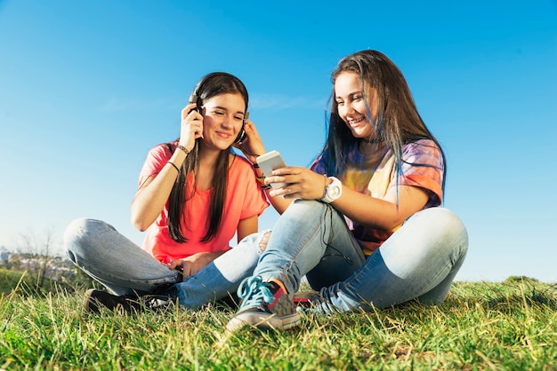 Photo happy beautiful teen friends in summer park listening music.