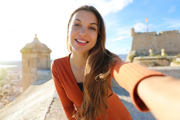 Happy beautiful tourist woman taking selfie photo in Alicante, Spain