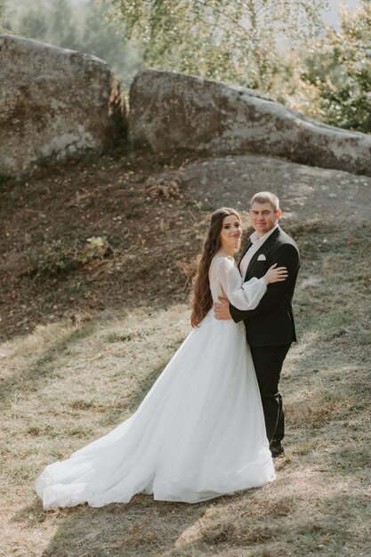 Happy beautiful wedding couple bride and groom at wedding day outdoors on the mountains rock.