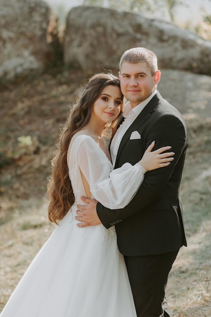 Happy beautiful wedding couple bride and groom at wedding day outdoors on the mountains rock.