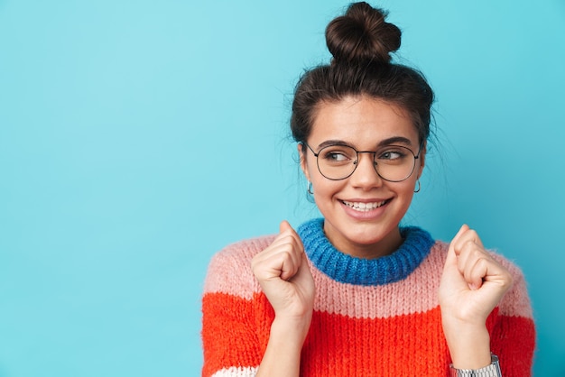 Photo happy beautiful woman in eyeglasses smiling and looking aside isolated over blue wall