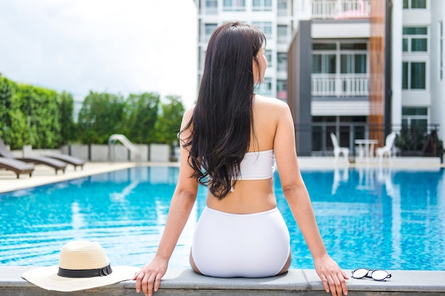 Happy beautiful woman lifestyle relaxing sitting near luxury swimming pool