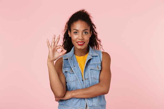 Happy beautiful woman posing isolated over pink wall showing okay gesture