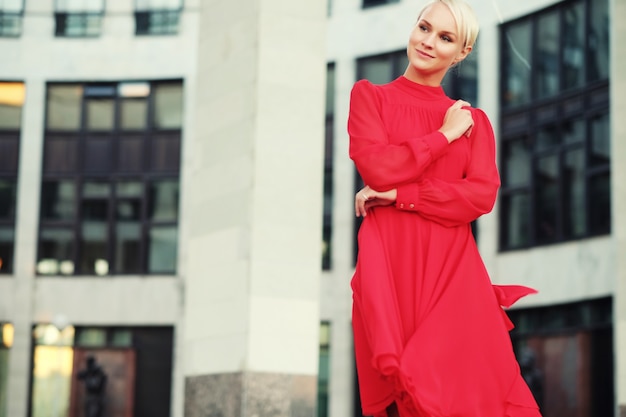 Happy beautiful woman in red summer dress walking and running joyful and cheerful smiling. Summer day.