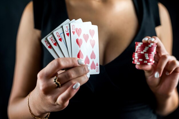 Happy beautiful woman in a seductive dress plays poker at the casino table